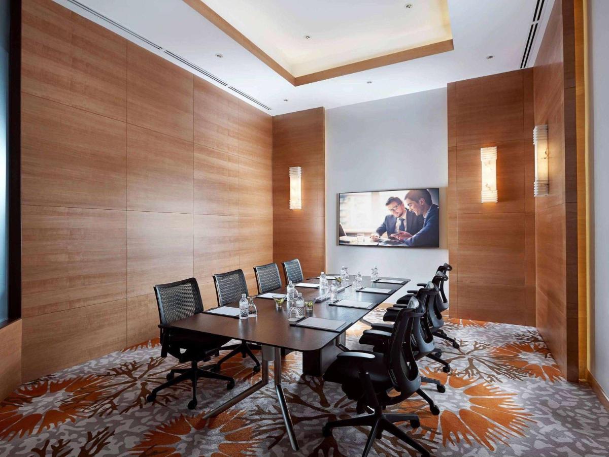 Paradox Singapore Merchant Court At Clarke Quay Εξωτερικό φωτογραφία The photo shows a modern conference room. It features a large rectangular table surrounded by several black chairs. The walls are primarily made of wood, creating a warm, sophisticated atmosphere. A large screen is mounted on one wall, displaying a p