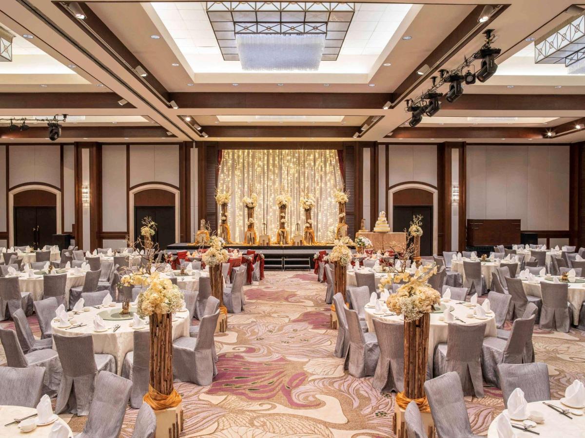 Paradox Singapore Merchant Court At Clarke Quay Εξωτερικό φωτογραφία The photo depicts an elegant banquet hall set up for an event. The room features numerous round tables draped in white and gray tablecloths, each adorned with floral centerpieces. The chairs are covered in gray fabric with white accents. At the front