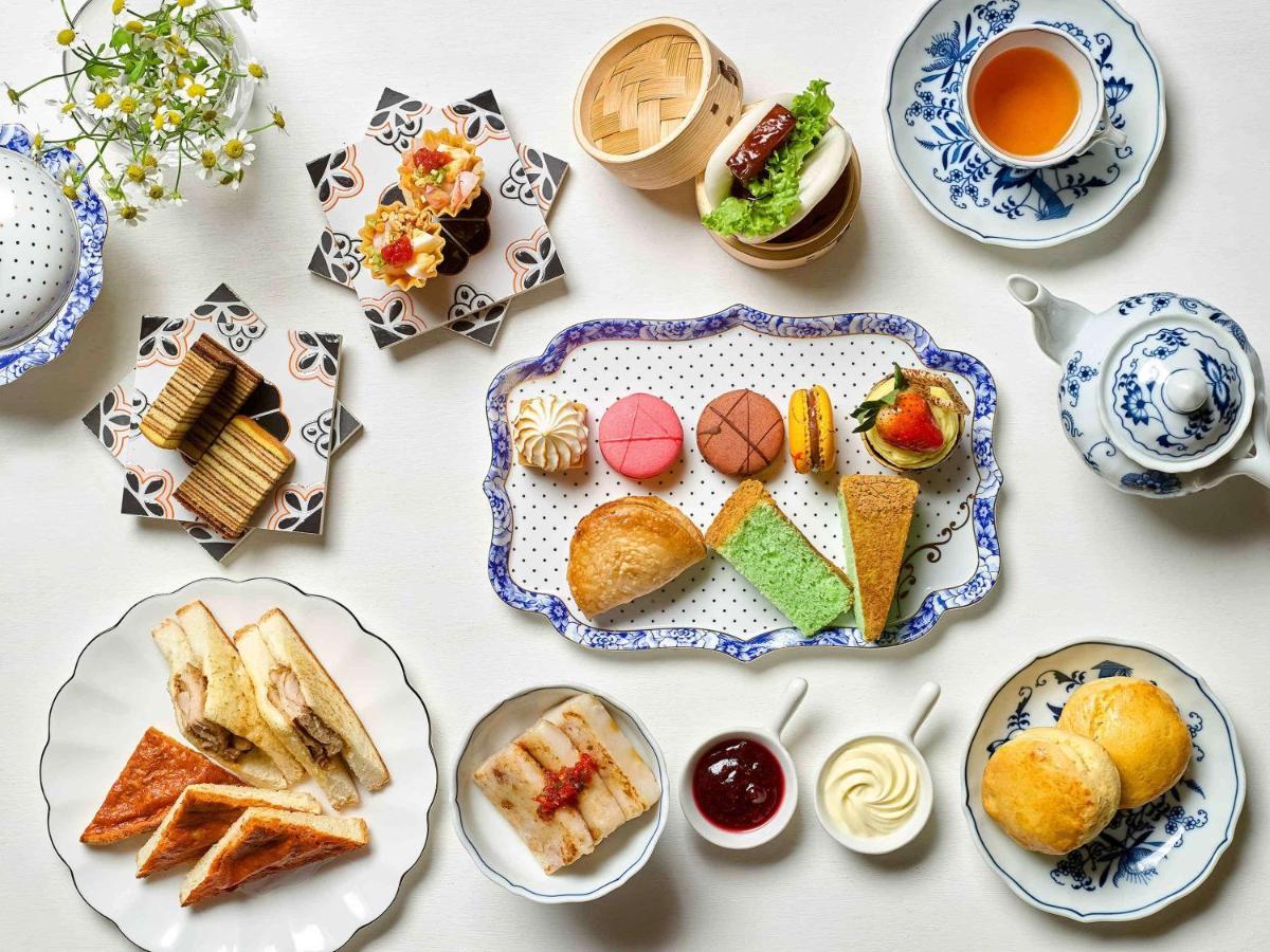 Paradox Singapore Merchant Court At Clarke Quay Εξωτερικό φωτογραφία The photo displays a beautifully arranged assortment of food items, likely presented for an afternoon tea or dessert setting. 

- In the center, there is a decorative platter featuring a variety of pastries, including colorful macarons, small cakes, 