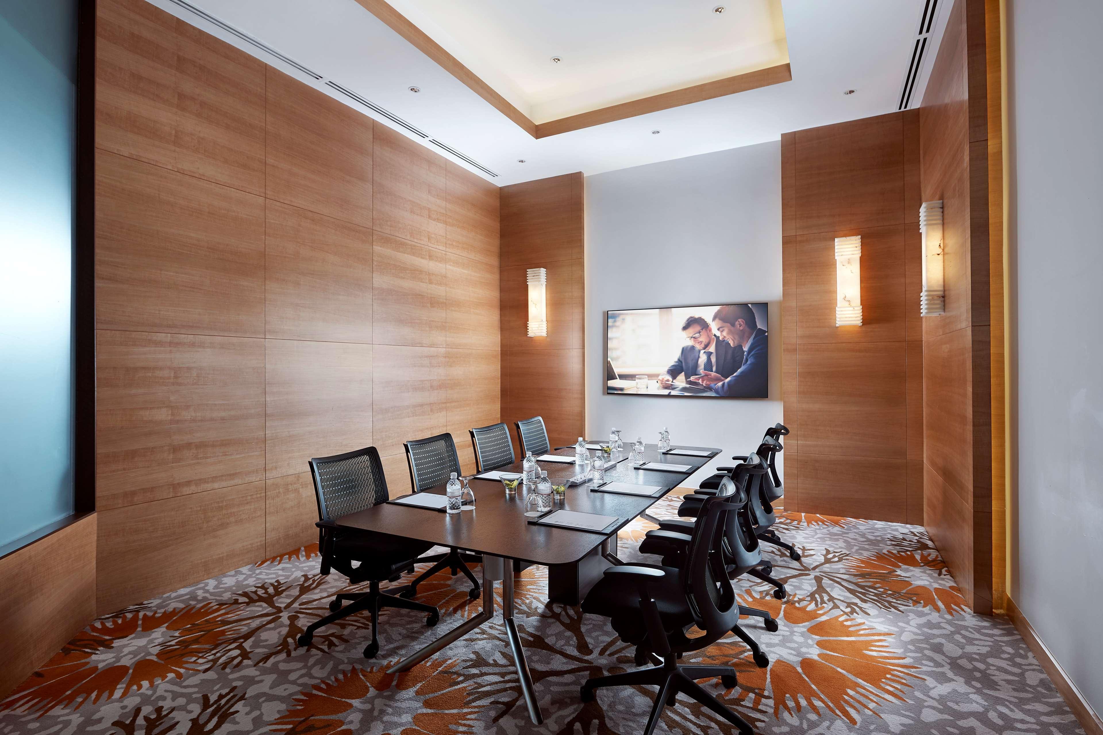 Paradox Singapore Merchant Court At Clarke Quay Εξωτερικό φωτογραφία The photo shows a modern conference room featuring a large wooden table surrounded by several black office chairs. The room has wooden paneling on the walls, creating a warm ambiance. There's a large screen mounted on one wall, likely for presentatio