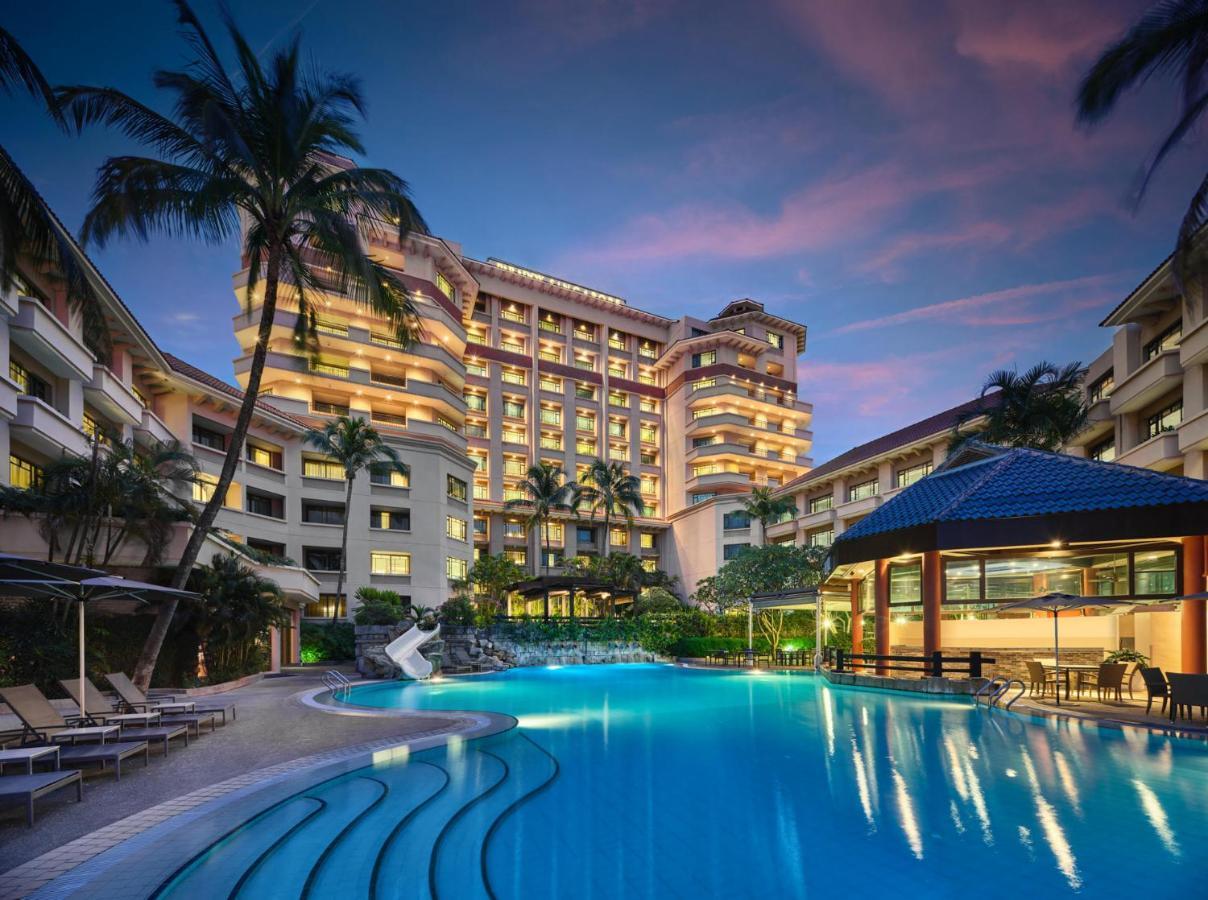 Paradox Singapore Merchant Court At Clarke Quay Εξωτερικό φωτογραφία The photo shows a luxurious hotel building, featuring multiple stories and a modern architectural design. In front of the hotel, there is a large, inviting swimming pool that is illuminated in a vibrant blue hue, suggesting it may be an evening setti