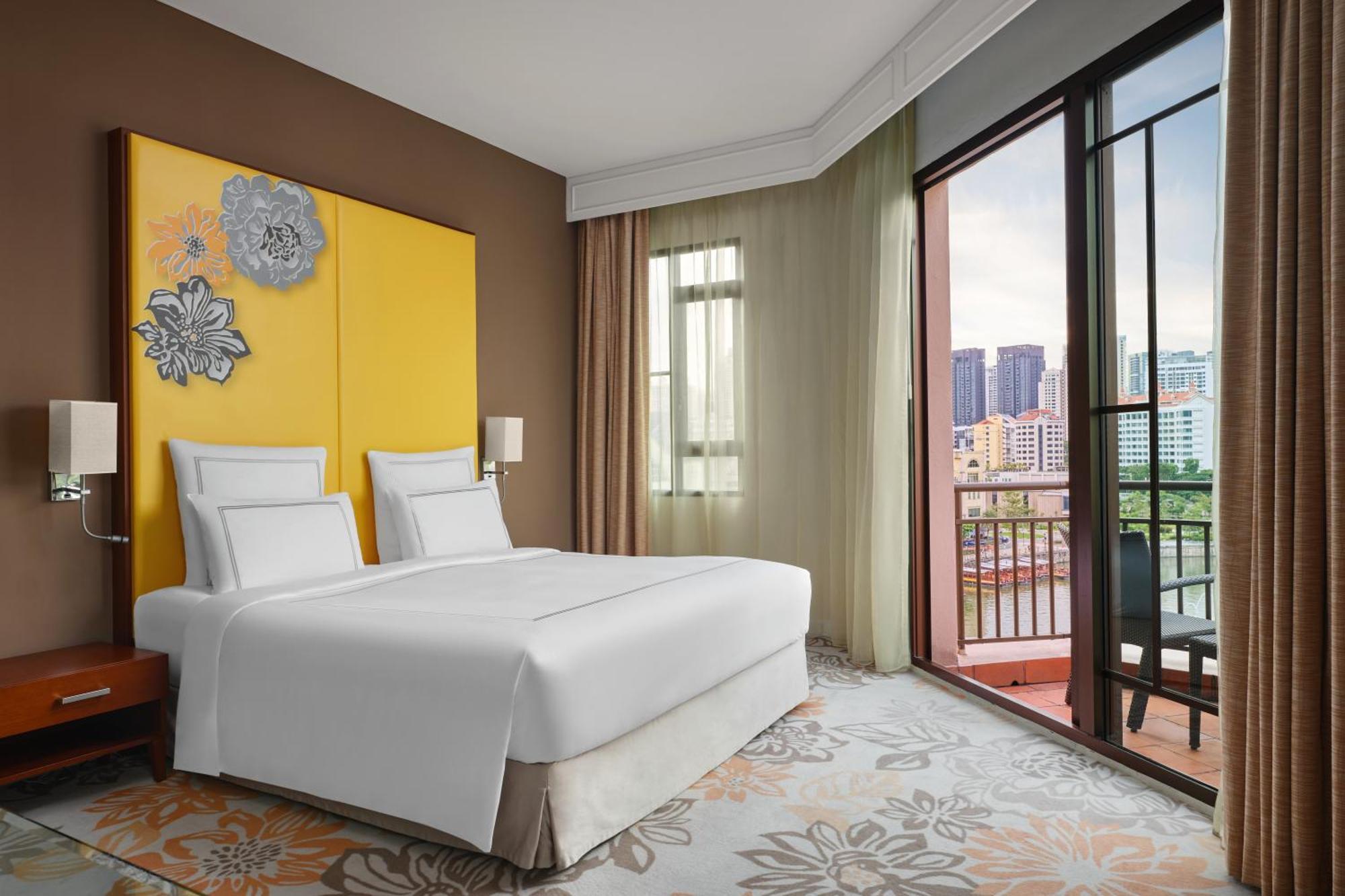 Paradox Singapore Merchant Court At Clarke Quay Εξωτερικό φωτογραφία The photo shows a modern hotel room featuring two beds with white linens placed against a yellow accent wall adorned with decorative elements. The room has large windows with sheer curtains, allowing natural light to enter and offering a view of the 