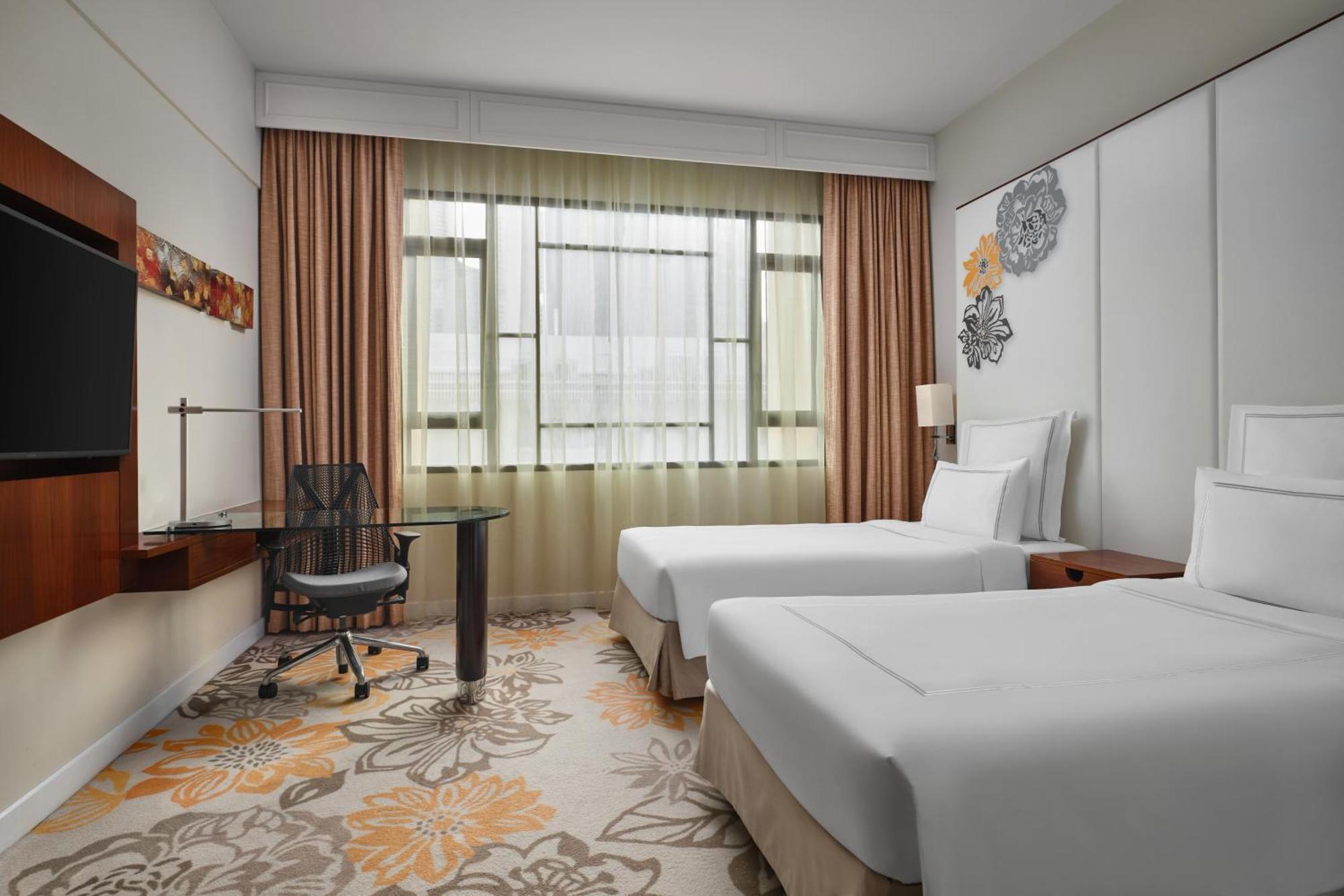 Paradox Singapore Merchant Court At Clarke Quay Εξωτερικό φωτογραφία The photo shows a modern hotel room featuring two twin beds with white bedding. There is a large window with sheer curtains allowing natural light to fill the space. In the corner, there's a stylish desk with an ergonomic chair. The room has a light 